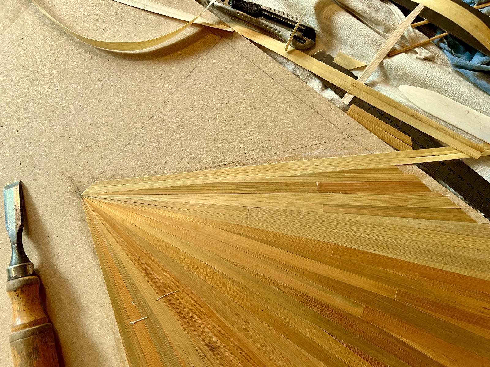 Skilled hands applying individual straws to create intricate marquetry patterns
