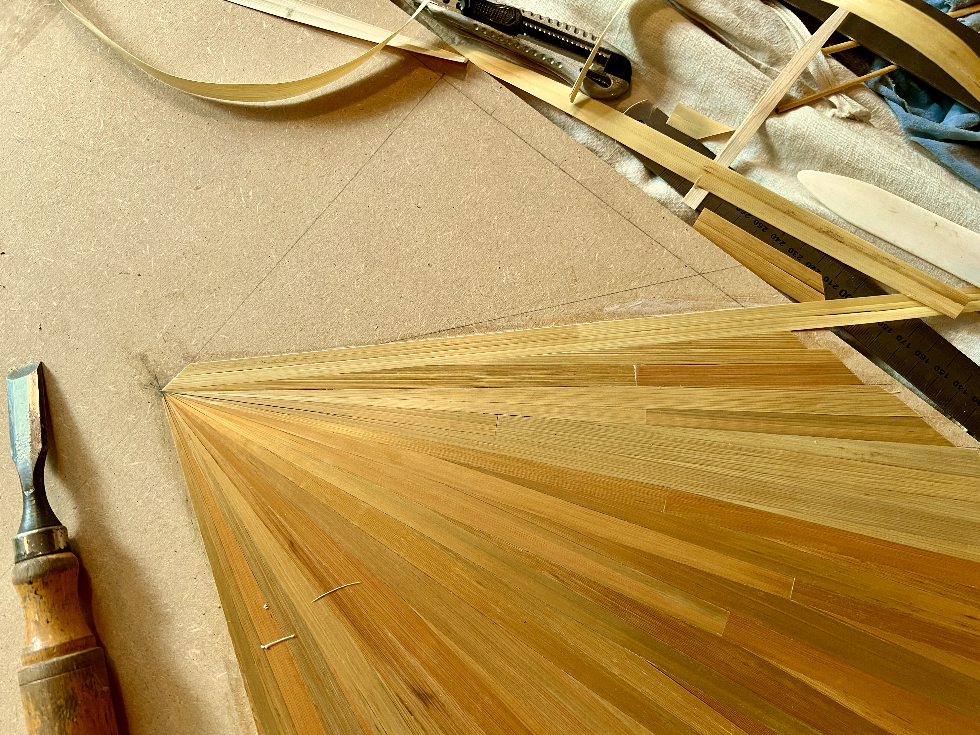 Skilled hands applying individual straws to create intricate marquetry patterns